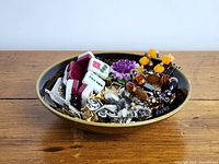 Top view of costume jewellery collection inside ceramic bowl on wooden surface