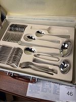 Foam tray with assorted serving utensils including forks, spoons, ladles and tongs