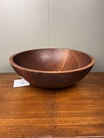 Side view of large wooden bowl on wooden surface, showing round shape and depth
