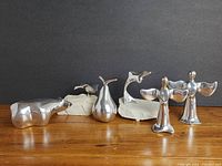 View of all six Hoselton aluminum figurines and sculptures arranged in a row showing variety of shapes and bases.