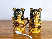 Front view of honey bear creamer and sugar bowl with one white spoon in front.