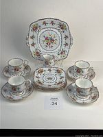 Photo of full set including cake plate, dessert plates, cups, saucers, and creamer arranged against white background.