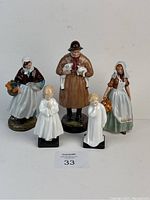 Five Royal Doulton figurines arranged with two child figurines in front and three adult female figurines behind, showing overall lot