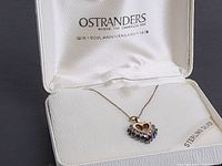 Heart-shaped sterling silver pendant with diamond and garnet stones on a silver chain in an Ostranders box.
