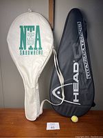 Two soft tennis racket cases, one white with green Snauwaert branding and one black with white Head Titanium Tennis branding, both showing marks and signs of wear