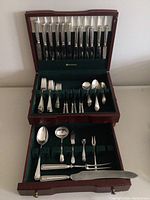 Birks Regency Plate silver cutlery set displayed organized in a wooden box with green lining showing knives, forks, spoons, and serving utensils in two tiers.