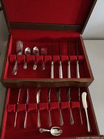 Full view of the Birks Regency Plate silver cutlery set arranged in a wooden box with red fabric lining, showing all pieces inside.