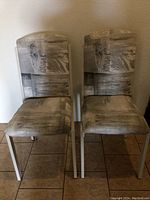 Photo of two metal framed chairs with grey and white abstract patterned fabric seats and backs, showing front and side views.