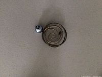 Top view of the brooch showing the spiral metal design and attached pearl on a gray background.