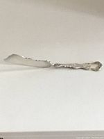Side view of the silver butter spreader showing the blade and part of the handle detail.