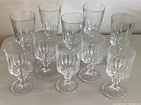 Ten clear crystal wine glasses arranged in two rows, 5 tall glasses in back and 5 smaller glasses in front, showing vertical fluted pattern on bowls.