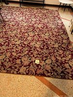 Photo of a large rectangular area rug with floral pattern and burgundy background, showing overall design and color.