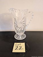 Single clear crystal glass decanter pitcher with pinwheel and starburst cut patterns, spout, and twisted handle.