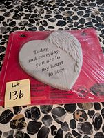Heart-shaped garden stone on red packaging with message engraved and angel wing decoration.