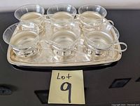 Silver plated tray with 6 clear glass cups nested in silver plated holders with handles.