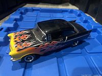 Front three-quarter view of the black Chevrolet diecast car model showing yellow and orange flames on hood and side.