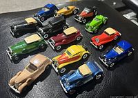 Photo of all 13 vintage Hot Wheels classic cars in various colors and models displayed together on a dark surface