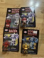 Four 1980s Esso Robot Racers Go Bots in original carded packaging displayed on a wooden floor showing condition and lot grouping