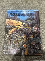 Front cover of Road Hogs RPG supplement showing illustrated combat scene of mutants in armored vehicles firing weapons in a street setting.
