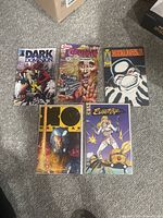 Top-down view of five comic books in protective bags on carpet. Titles visible: Dark Dominion, Grimjack, Dreadstar, Agent X Manowar #21, Evangelife.