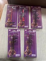 Five new Fortnite metal keychains in original purple packaging with Fortnite character art, each keychain shaped as different guns.