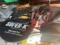 Two baseball gloves and a junior tennis racket with cover on display