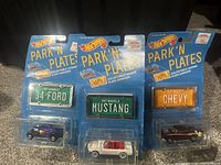 Three sealed Hot Wheels Park 'N Plates collectible license plate sets from 1988, showing front side of blister packs with cars and plates.