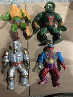 All four vintage Masters of the Universe action figures laid out on a surface showing full bodies and colors.