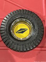 Photo of the top view showing the tire tread detail and Goodyear branding on the black tray with yellow Goodyear logo at center under glass dome.