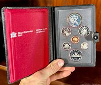 Photos of a 1983 Canadian proof coin set housed in a black and red leather case from the Royal Canadian Mint showing front and back sides of the coins.