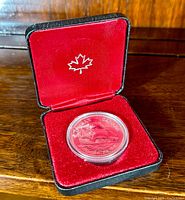 Coin housed in original black and red velvet-lined display case with maple leaf emblem