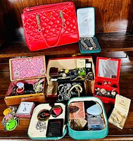 Wide shot of red Guess purse atop wooden shelf with multiple jewelry boxes and assorted pieces