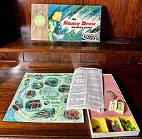 Game board laid flat showing the full illustrated game path with various locations and spaces, along with instruction sheet, small car tokens, cards, and colored chips arranged in box interior.