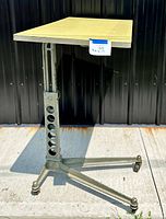 Full view of vintage desk showing yellow Formica top and cast iron adjustable base with castor wheels.