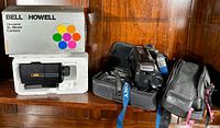 Bell & Howell Microstar XL Movie Camera in original box and packaging next to Sony Video 8 Handycam with carrying cases