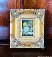 Front view of the small floral oil painting in ornate gilded baroque frame.