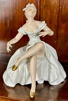 Front view of the porcelain ballerina figurine showing detailed facial features, ruffled dress, and gold ballet shoes.