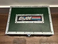 Closed green metal-style box with G.I. Joe logo on top and rivet detailing