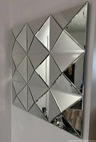 Side angle view showing the three-dimensional diamond pattern of beveled triangular and diamond-shaped mirrored panels on the square mirror.