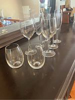 View of eight assorted wine glasses arranged in two rows, four stemmed and four stemless glasses