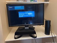 Samsung 20-inch monitor with 'No Signal' screen displayed, Amazon Echo smart speaker beside it, and black laptop stand below