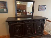 Front view of antique wooden china chest with three carved cabinet doors and drawers above; dark wood with worn finish.