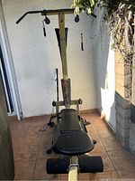 Front angle view of Bowflex Ultimate Resistance machine with overhead pull bar, bench, and resistance cables.