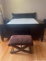 Full view of the California King bed showing the dark stained wooden frame and mattress on top