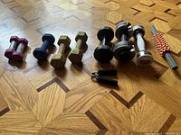 Wide view of all dumbbells and hand grip exerciser arranged on parquet floor