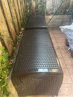 Two storage benches side by side against wooden fence