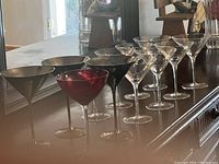 Photo showing entire set of 12 martini glasses arranged in rows, including 8 clear, 3 gold-colored, and 1 red glass.