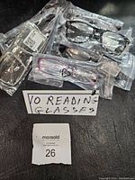 Photo showing multiple pairs of new reading glasses individually packaged in clear plastic bags, various colors visible