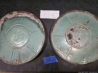Two rusted metal film reels side by side on black surface with handwritten note 'Stranger Than Science Fiction Movie'