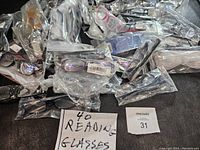 Top view of multiple individually bagged reading glasses in various frame colors and styles arranged together showing diversity in design.